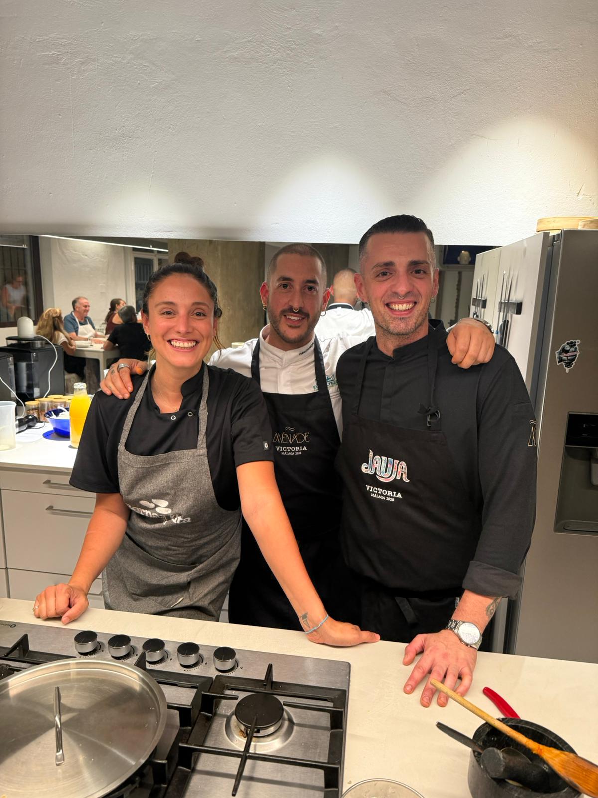 Tres cocineros con delantales posando sonrientes en la cocina de OCOA Culinary Space en Málaga