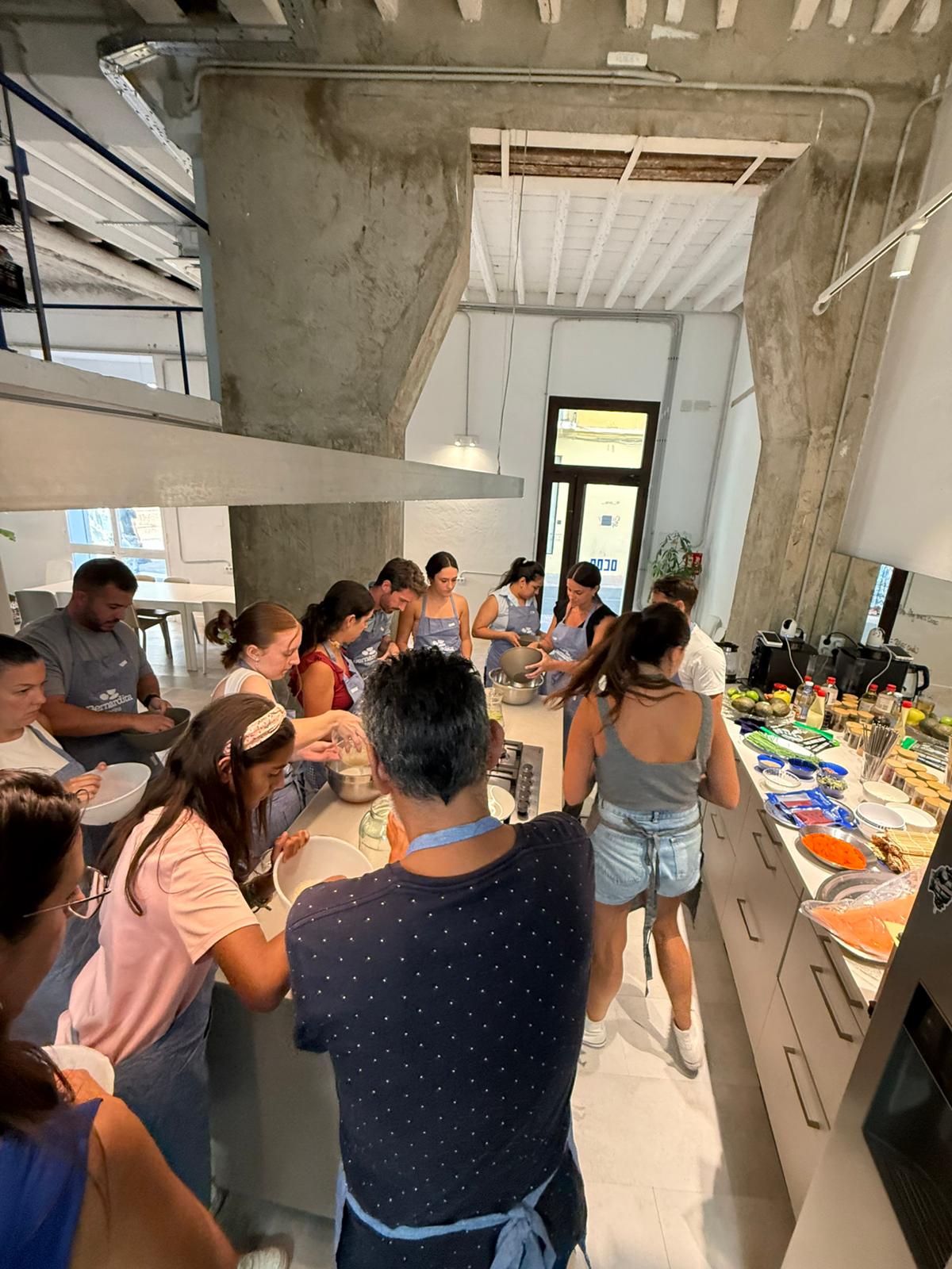 Grupo de personas con delantales cocinando juntos en el espacio OCOA Culinary Space, taller de cocina en Málaga